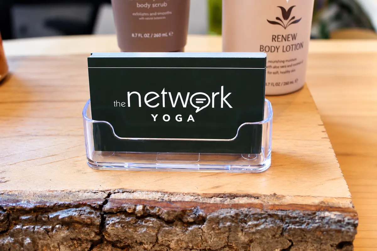 The Network Yoga business cards in a clear holder beside body care products